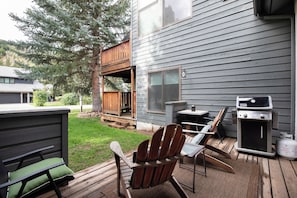 Una terraza con mobiliario exterior, una parrilla y una mesita.