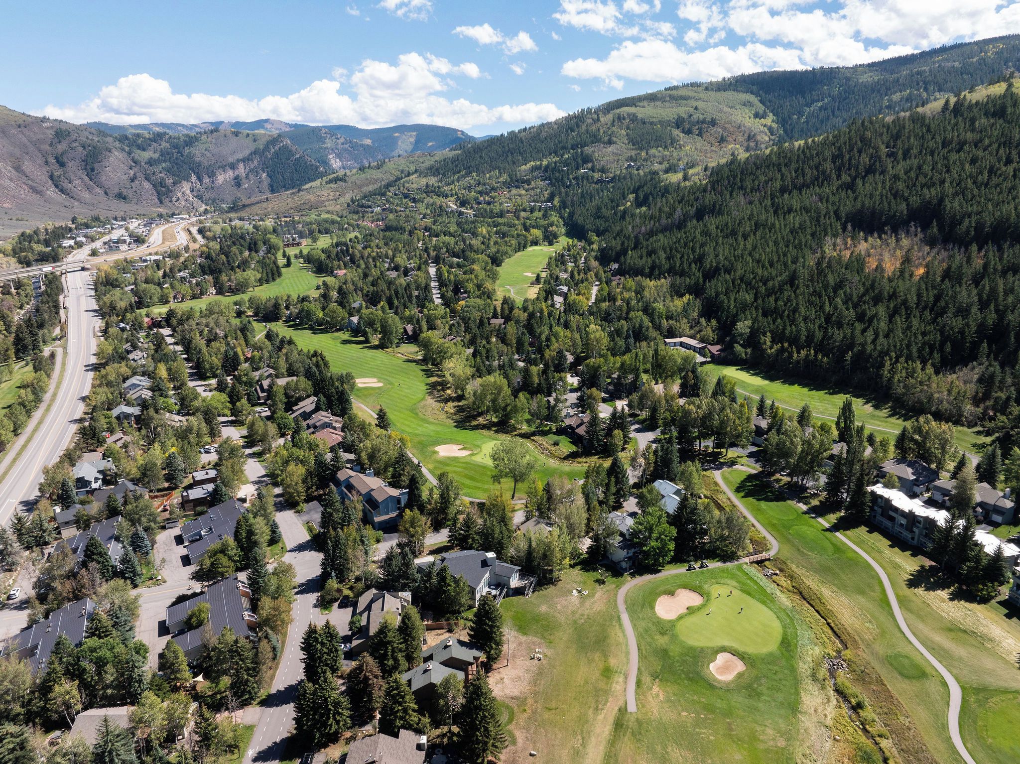 A residential area with houses, roads, and a golf course.
