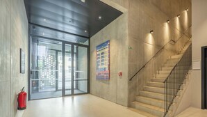 Ein modernes Interieur mit Treppe, Feuerlöscher und Glastür zum Außenbereich.