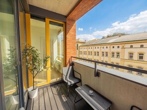 Ein Balkon mit Holzboden, einem Blumentopf, einem Stuhl und einem Tisch.