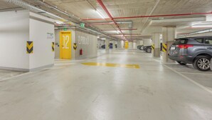 Eine mehrstöckige Parkgarage mit Betonpfeilern, gelben Pfeilen zur Orientierung und einigen parkenden Autos.