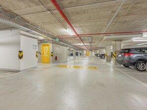 Eine mehrstöckige Parkgarage mit Betonpfeilern, gelben Pfeilen zur Orientierung und einigen parkenden Autos.