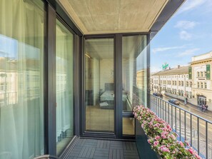 A balcony with a view of a street and buildings, a glass door, and a flower arrangement. - Beautiful apartment for 6 guests with WIFI, TV, balcony and pets allowed (Prague)
