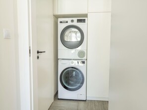 A compact laundry room with a front-loading washer and dryer stacked vertically. - Beautiful apartment for 6 guests with WIFI, TV, balcony and pets allowed (Prague)