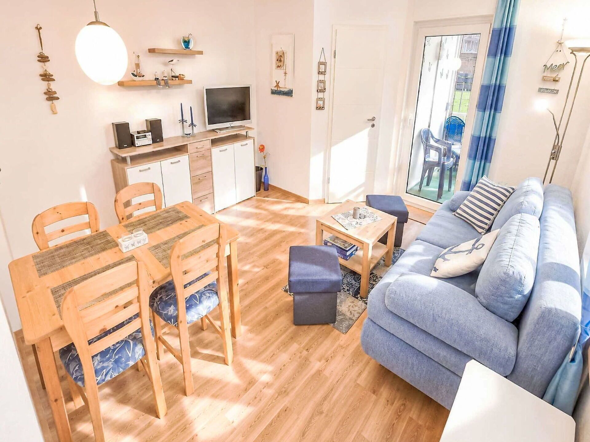 Una sala acogedora con sofá, una mesa de comedor con sillas, televisor y una zona de cocina con armarios y encimera.