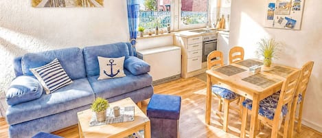 A compact living space with a sofa, a dining table, and a kitchenette.