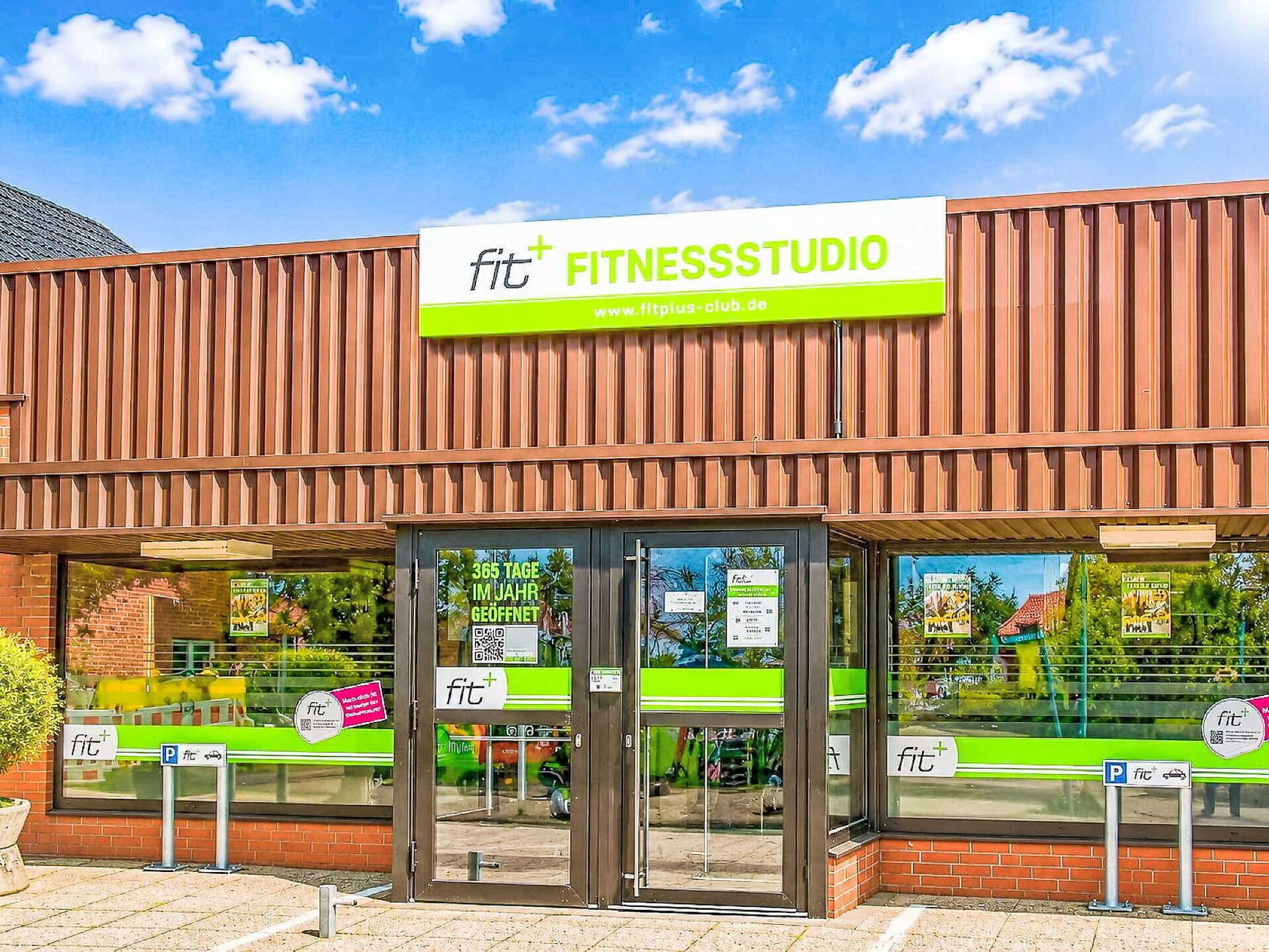 Un estudio de fitness con un letrero llamativo, puertas de vidrio y señal de estacionamiento.