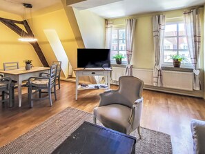 Een woonkamer met een eethoek, een flatscreen televisie, een bank en een fauteuil.