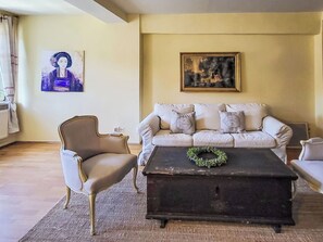 Un salon comprenant un canapé, un fauteuil et une table basse sur laquelle est posée une couronne décorative.