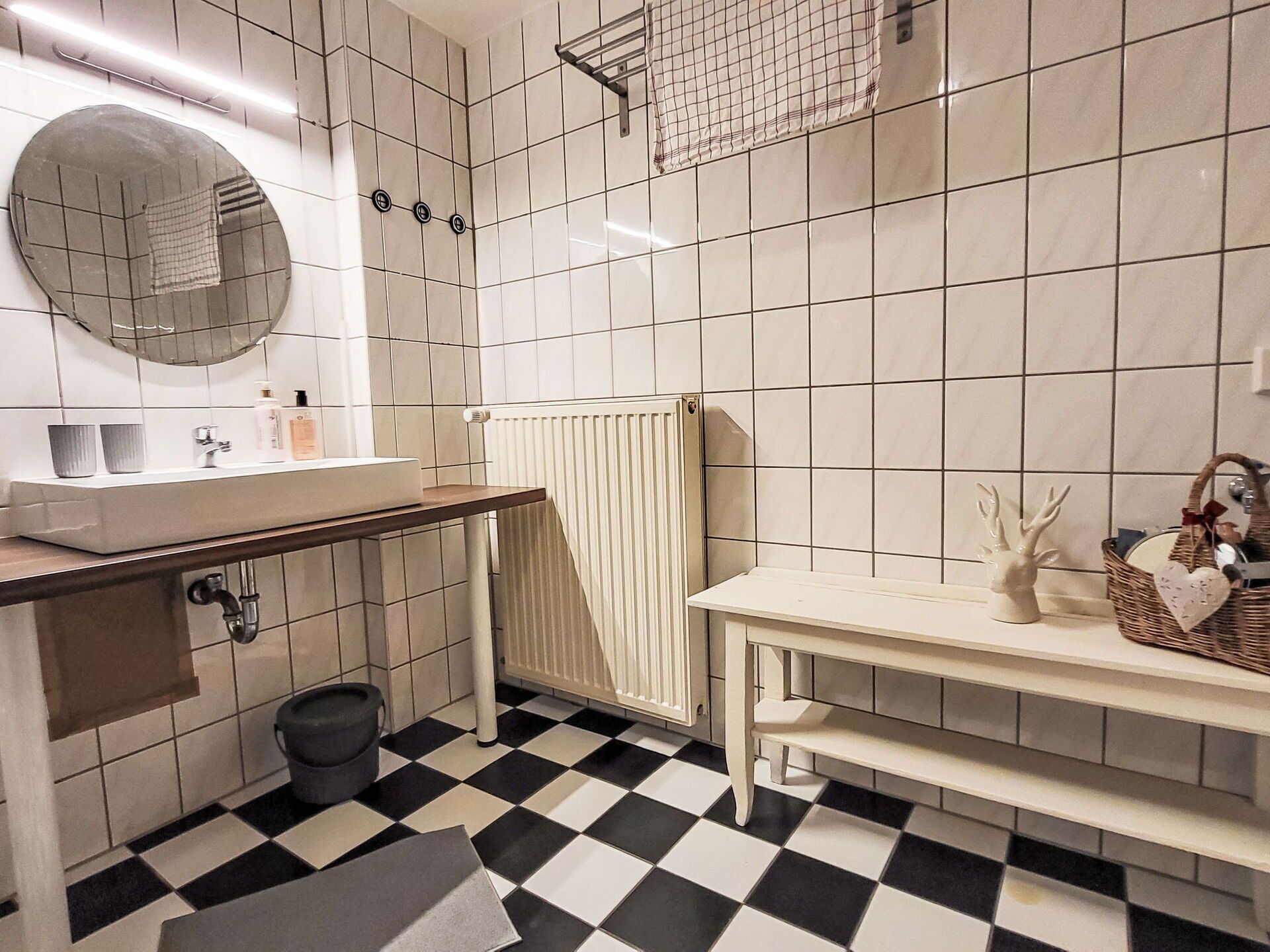 A bathroom with a checkered floor, a sink with a mirror, and a towel rack.
