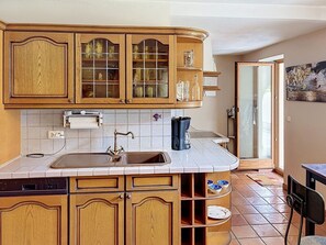 A kitchen with wooden cabinets, a sink, and a tiled backsplash.