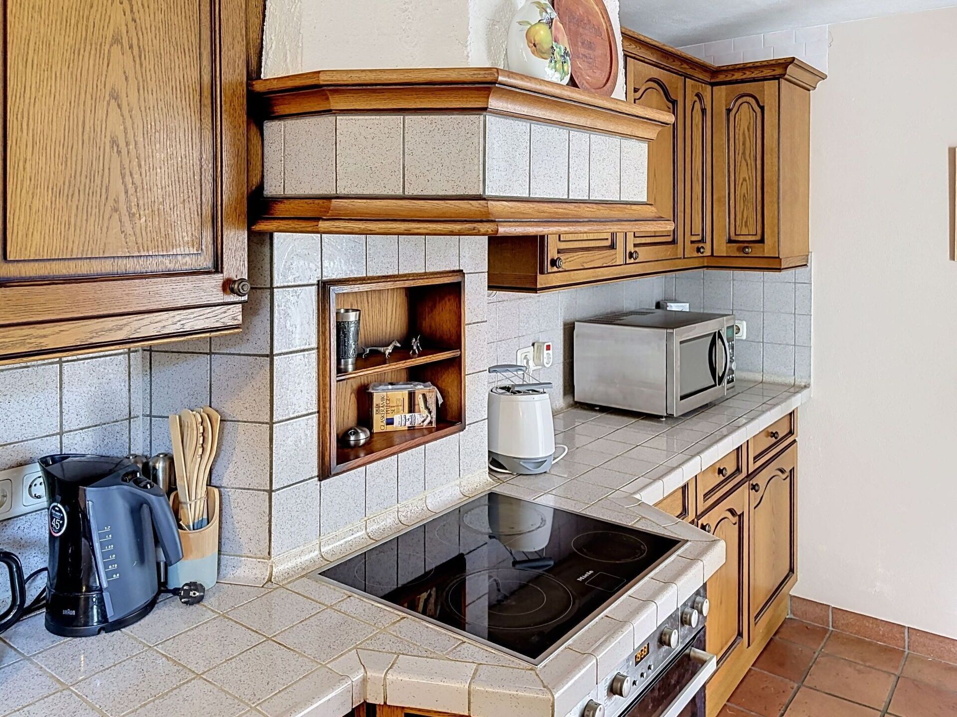 A kitchen with wooden cabinets, a microwave, a toaster, and a stove.