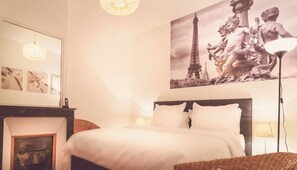 A hotel room with a bed, a nightstand, a lamp, a painting of the Eiffel Tower, and a mirror. - Very Quiet 1 Br by Rue Cler, short walk to Eiffel Tower, Nearest metro 2min walk (Paris)