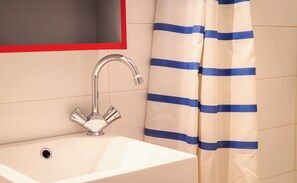 A bathroom with a white sink, a chrome faucet, and a striped shower curtain. - Very Quiet 1 Br by Rue Cler, short walk to Eiffel Tower, Nearest metro 2min walk (Paris)