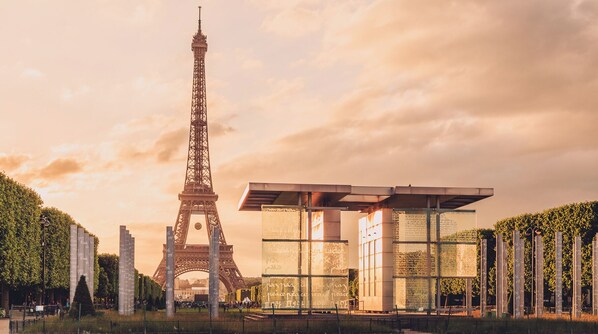 The Eiffel Tower with a modern glass structure in the foreground.