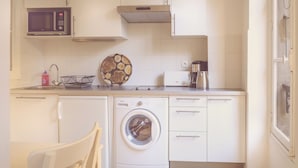 Una cocina compacta equipada con lavadora, microondas y cafetera.