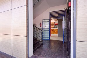 Un couloir avec un escalier menant à une pièce aux couleurs rouge et blanche.