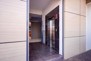 A hallway with a closed elevator and a blue door.
