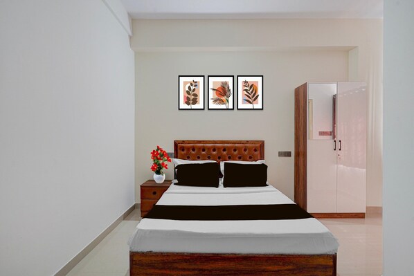 A bedroom with a bed, a nightstand, a dresser, and three framed pictures on the wall.