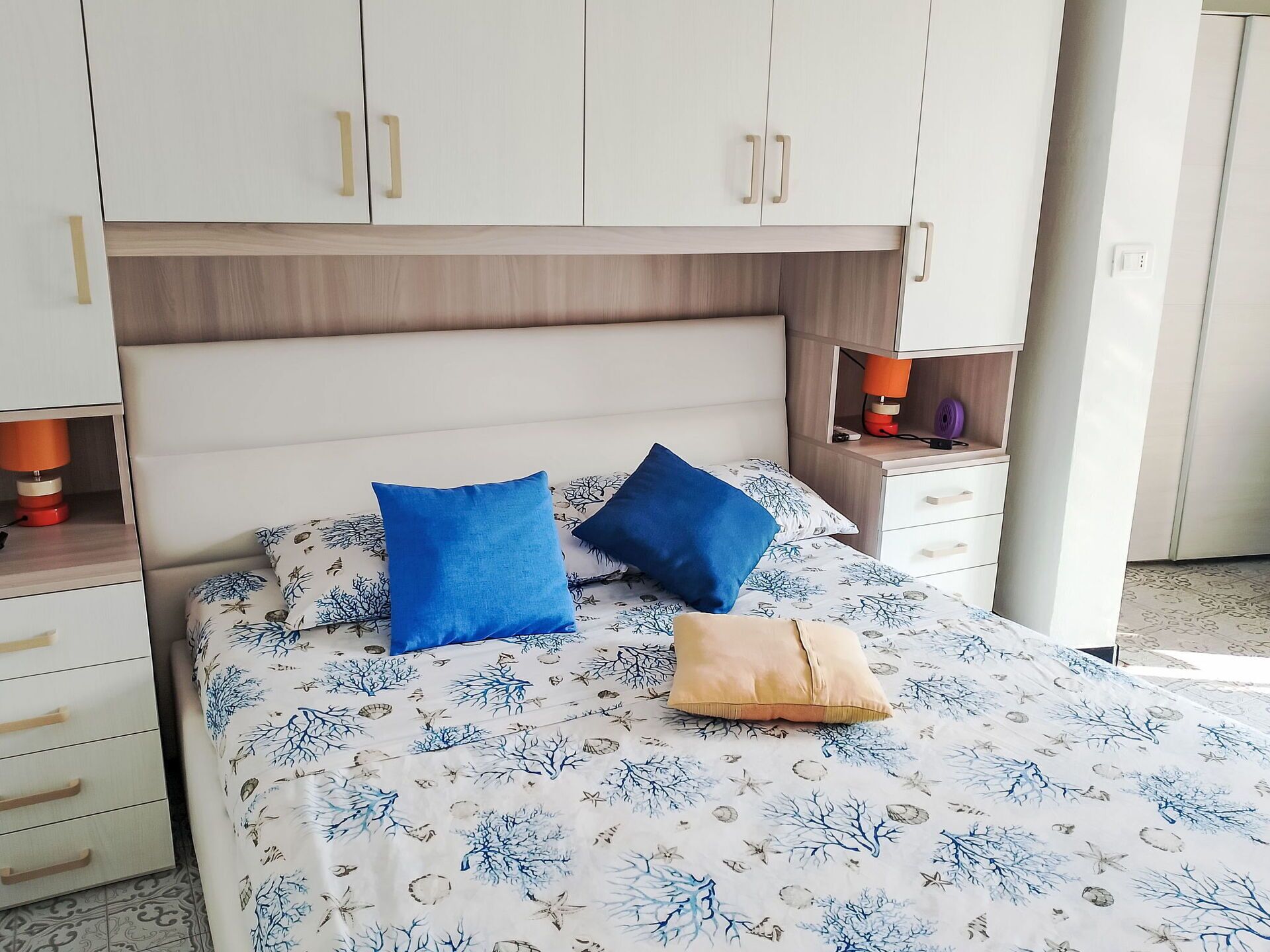 Une chambre à coucher avec un lit, deux oreillers, une table de chevet, une lampe et une armoire.