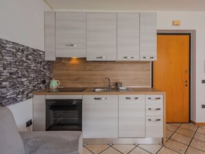 Cuina compacta amb forn integrat, un bany i una porta de fusta.