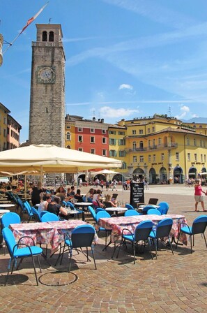Une place avec des terrasses, une tour de l’horloge et des bâtiments aux couleurs vives.