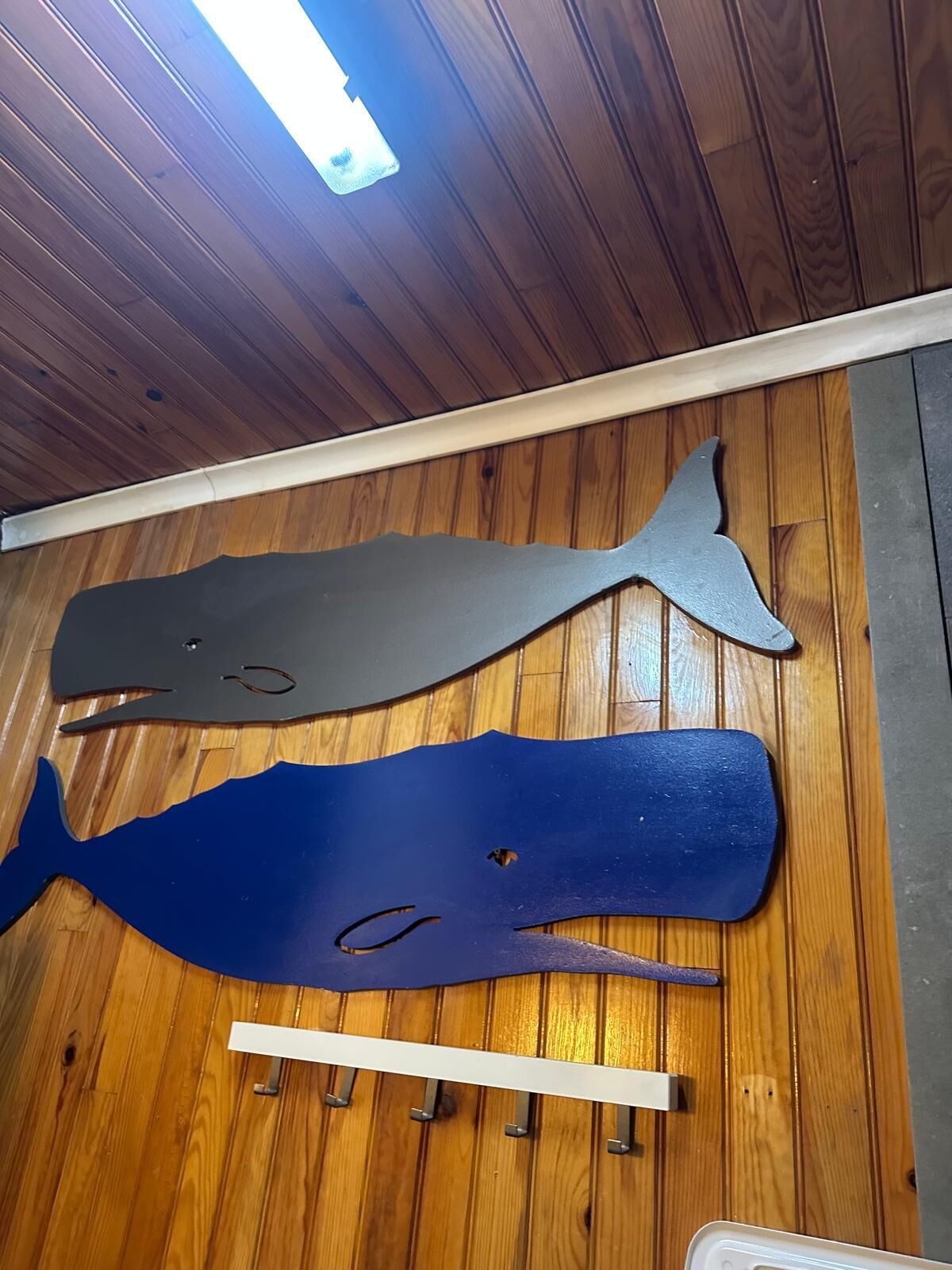 Two whale-shaped wall decorations on a wooden floor.