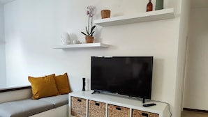 A modern living room with a flat-screen TV, a sofa with cushions, and storage baskets. - Refined structure in Milazzo, designed to experience an exclusive stay. (Milazzo)