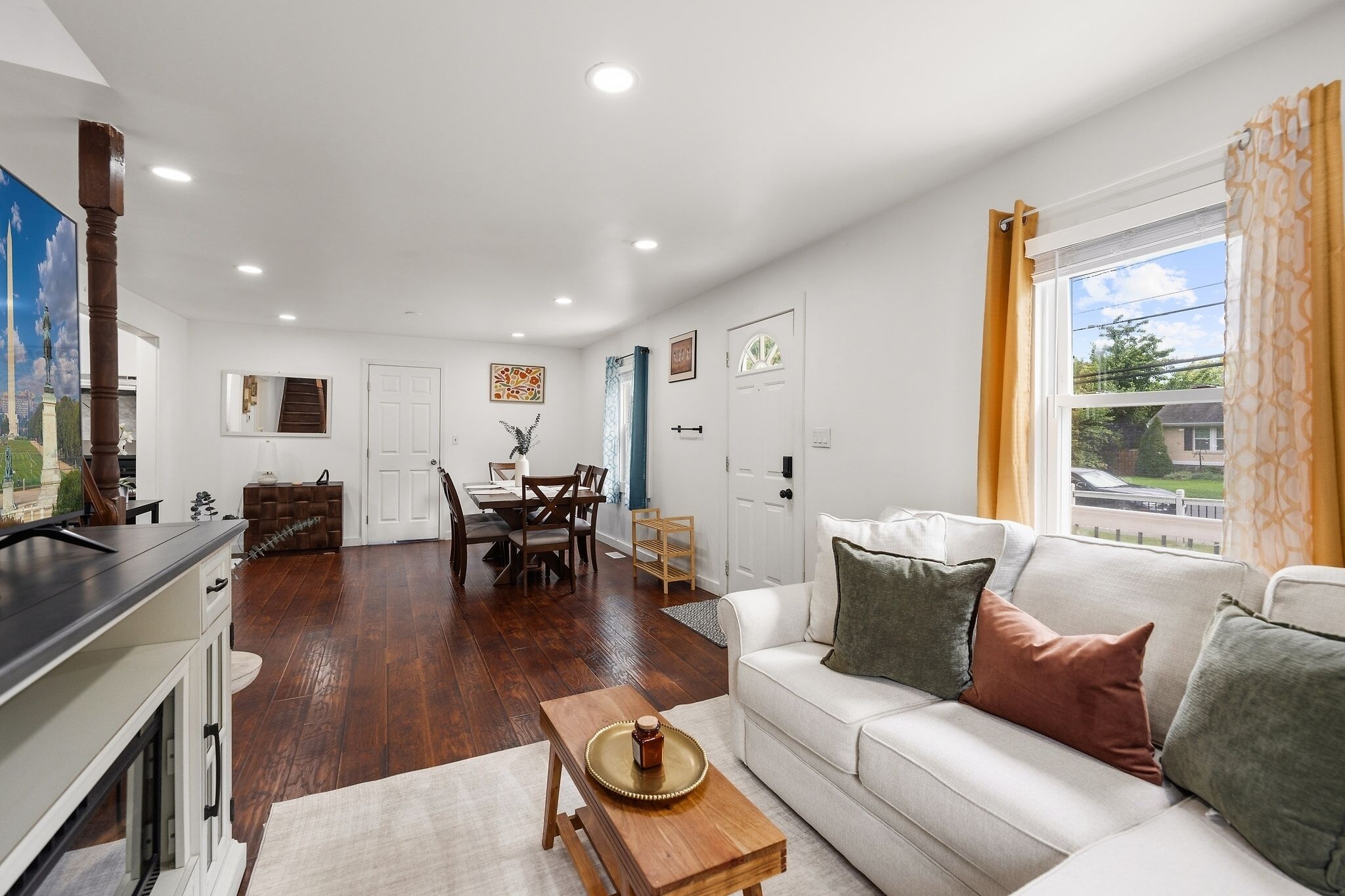 A well-lit living room with a sofa, coffee table, and dining area.