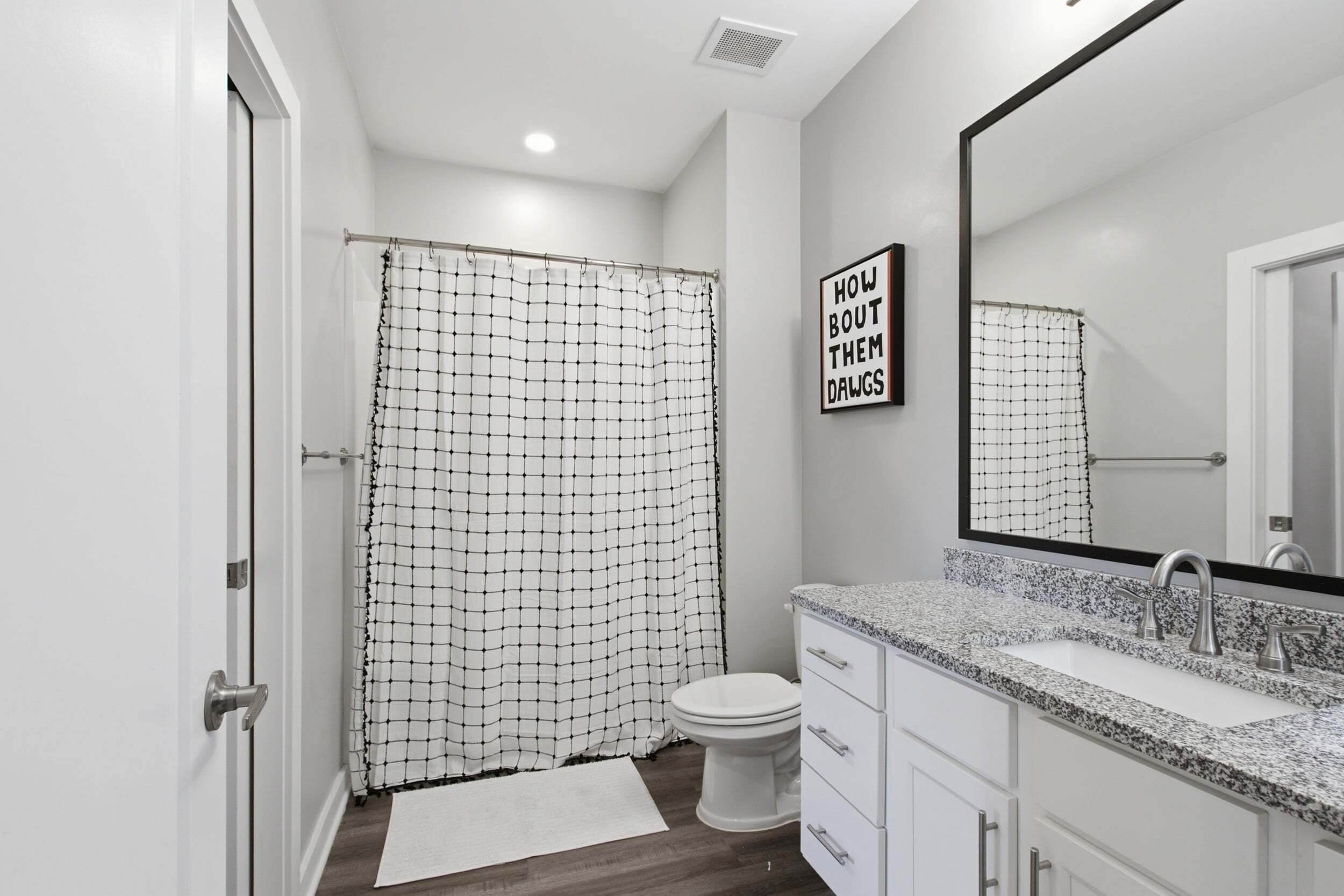 A modern bathroom with a shower curtain, toilet, sink, and a mirror.