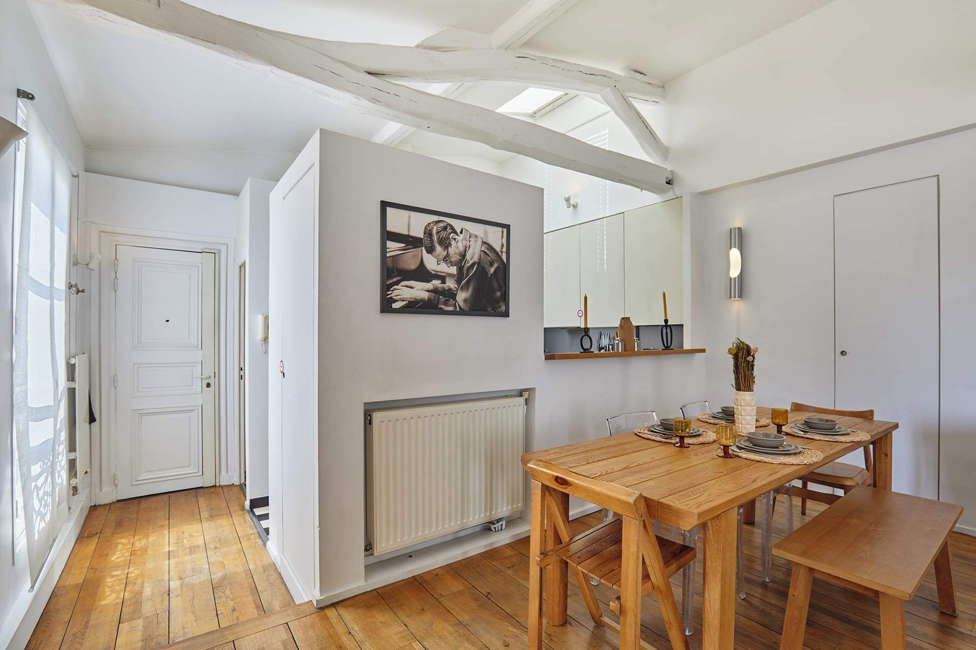 Un comedor con una mesa y sillas de madera, un radiador blanco y un cuadro en la pared.