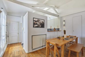 Un comedor con una mesa y sillas de madera, un radiador blanco y un cuadro en la pared.