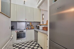 Eine kompakte Küche mit einem Edelstahlkühlschrank, einem Einbauofen und einer Mikrowelle.