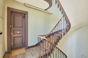 Eine hölzerne Treppe mit geschwungener Form, eine Tür mit Knauf und eine Leuchte darüber.