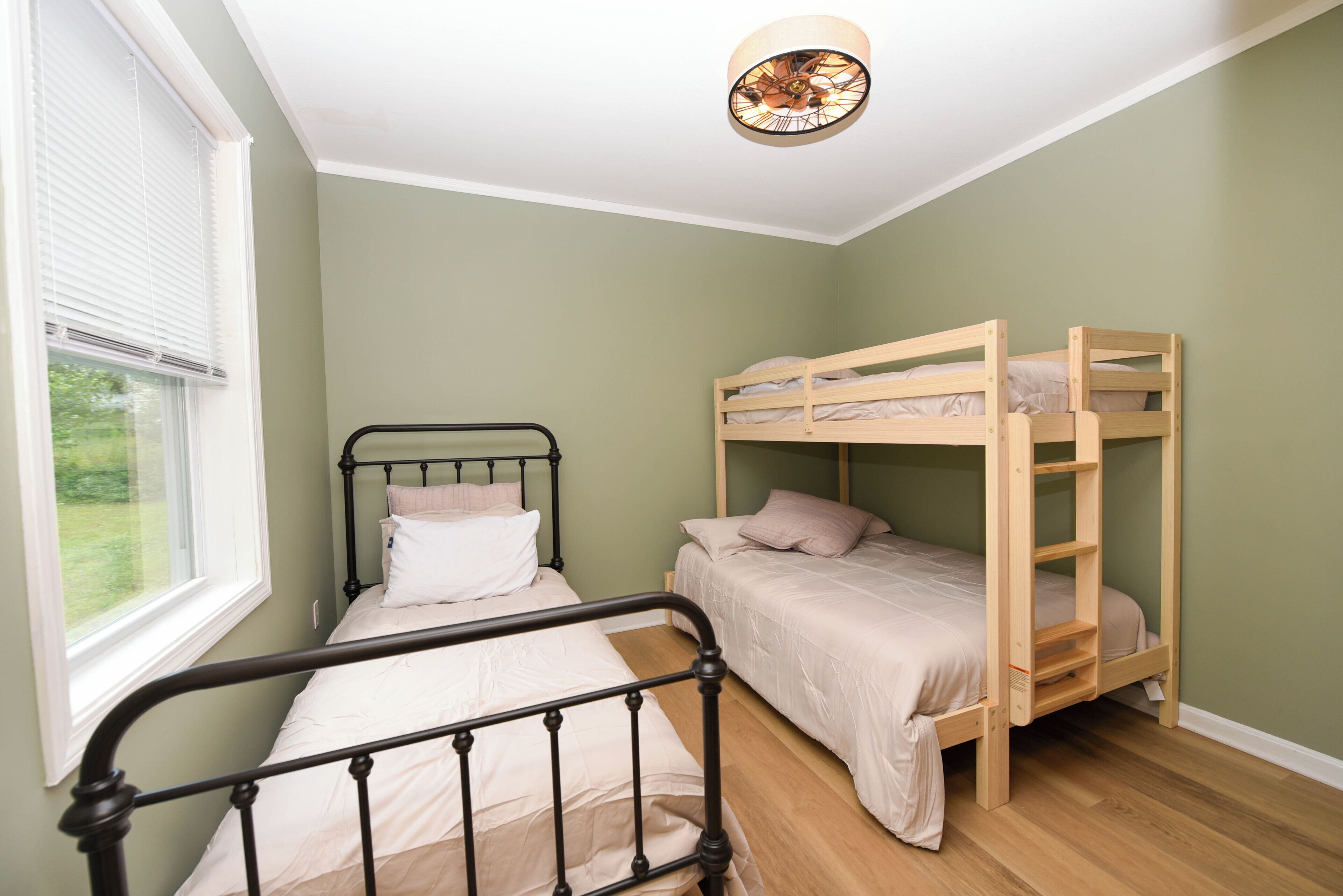 Un dormitorio con una cama individual, una cama litera y un ventanal con persianas.