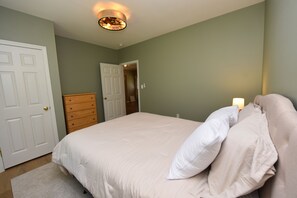 Een slaapkamer met een bed, een dressoir en een deur.