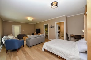 A modern hotel room with a bed, a sofa, a desk, and a television. - Peaks & Paws -Pet friendly, single level, sleeps 8 close to beach (Conway)