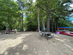 Ein Campingplatz mit Picknicktischen, Platz für Kanus und einem Boden aus Erde.