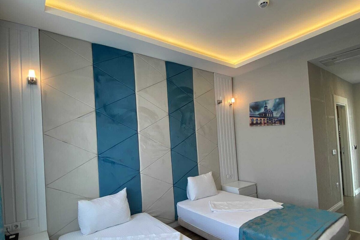Ein Hotelzimmer mit zwei Betten, einem Bild an der Wand und Blick auf den Flur.