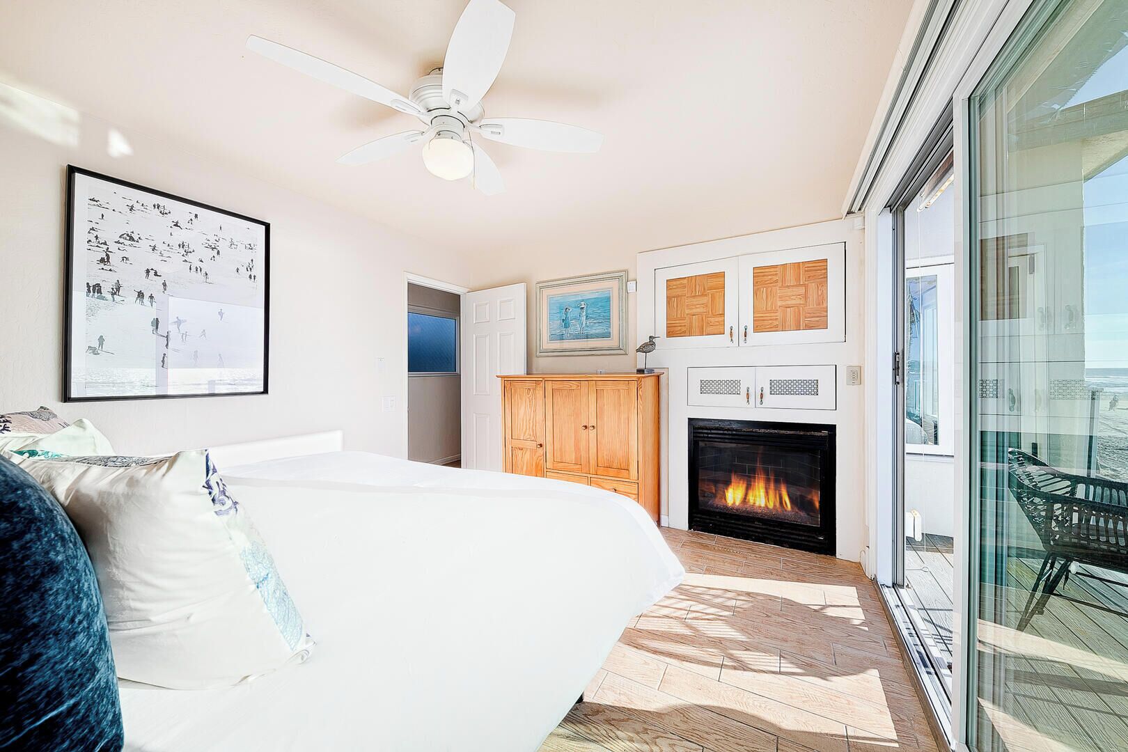 Une chambre à coucher avec un lit, un ventilateur de plafond, une cheminée et une vue sur l’extérieur.