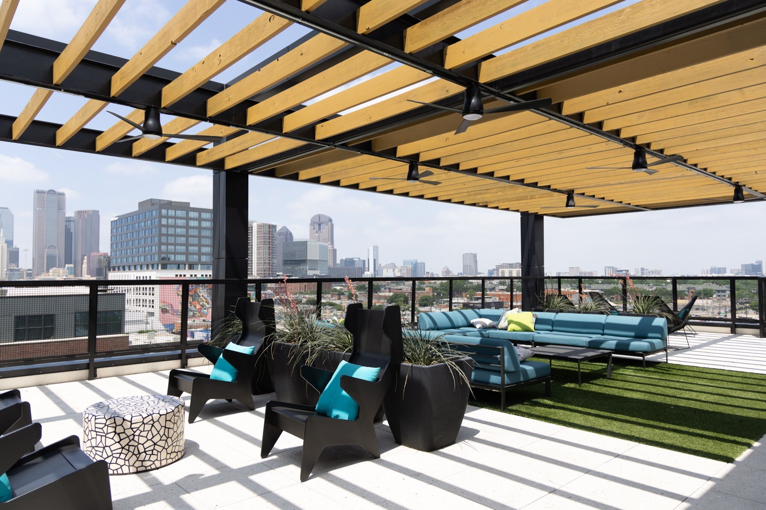 A rooftop terrace with a city view, outdoor seating, and a pergola structure.