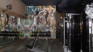 A gym with a graffiti-covered wall, weightlifting equipment, and dumbbells. - Modern Deep Ellum Loft with Rooftop Pool & Downtown Dallas Skyline Views (Dallas)