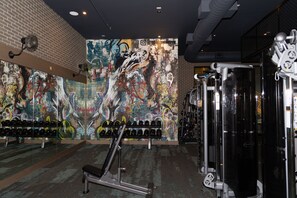 A gym with a graffiti-covered wall, weightlifting equipment, and dumbbells. - Modern Deep Ellum Loft with Rooftop Pool & Downtown Dallas Skyline Views (Dallas)