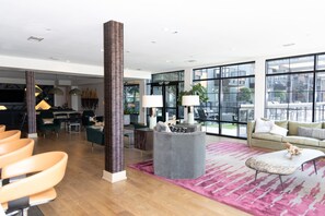 A spacious living area with a large window, a high ceiling, and a modern interior design.