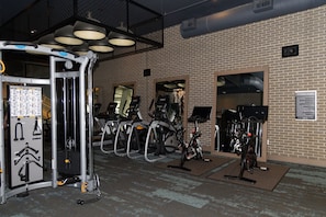A fitness center with exercise equipment, including treadmills and stationary bikes, and a wall-mounted sign indicating the area.