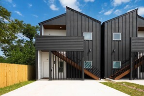 A modern two-story building with a flat roof, a wooden fence, and a clear sky. - 3BR Modern Home, 15 Min to Downtown, Hobby, & NRG (Houston)