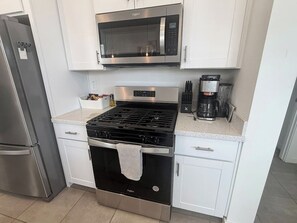 A kitchen with a stainless steel refrigerator, a microwave, a stove, and a coffee maker. - Modern 3BR Casa Grande Retreat | Pool Access + I-10 (Casa Grande)