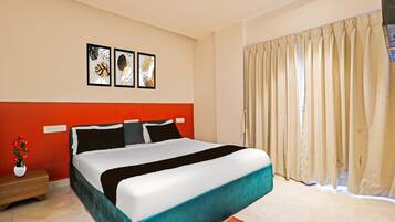 A hotel room with a bed, a nightstand, a vase of flowers, and a window with curtains.