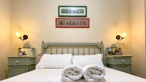 A bed with white linens, two pillows, and a folded towel on the bed. There are two bedside tables with lamps and a framed sign above the bed. - Charming Seville Center Alameda (Sevilla)