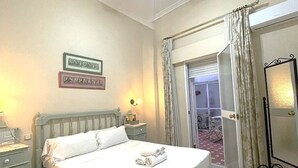 A neatly made bed with white linens, a bedside table with a lamp, and a mirror on the wall. - Charming Seville Center Alameda (Sevilla)